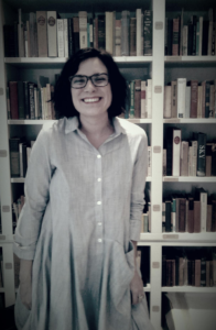 Portrait of Bivens smiling in front of a filled bookcase