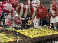 photo of interior of grocery store focusing on valentine balloons (red) above bananas (yellow)